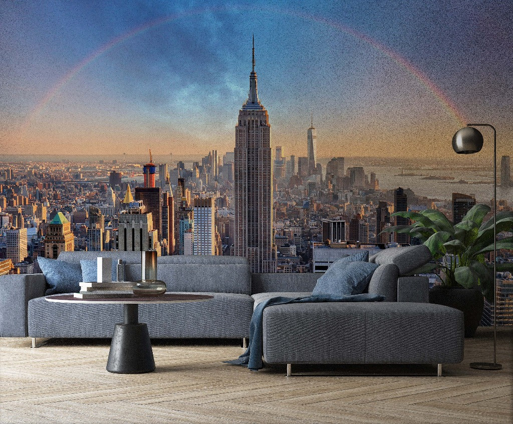 Living Room - A modern living room features a Decor2Go Wallpaper Mural titled Double Rainbow Skyline with an iconic skyscraper at the center and a subtle rainbow in the sky. The room includes a sectional sofa, a round coffee table, and a floor lamp, with potted plants adding a touch of greenery to the urban aesthetic decor.