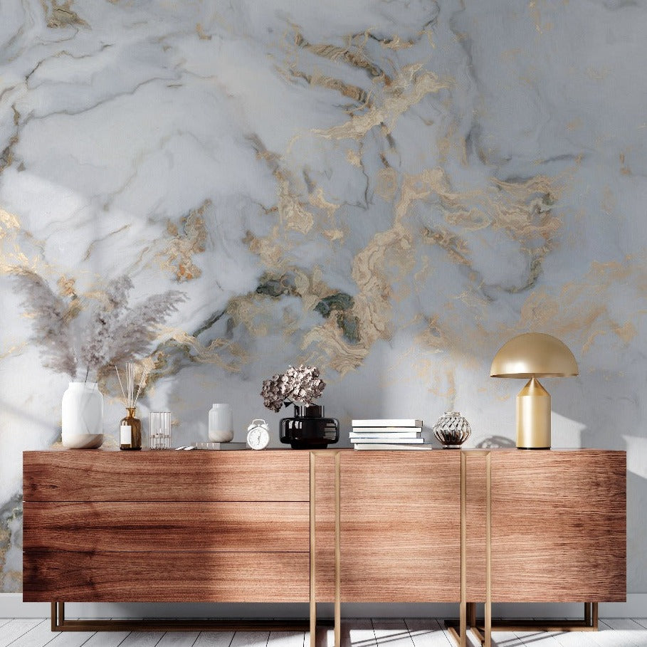 A modern living room with a wooden sideboard against a Decor2Go Wallpaper Mural wall with gold veins. On top are decorative vases, books, and a stylish gold lamp, set on a light wooden floor.