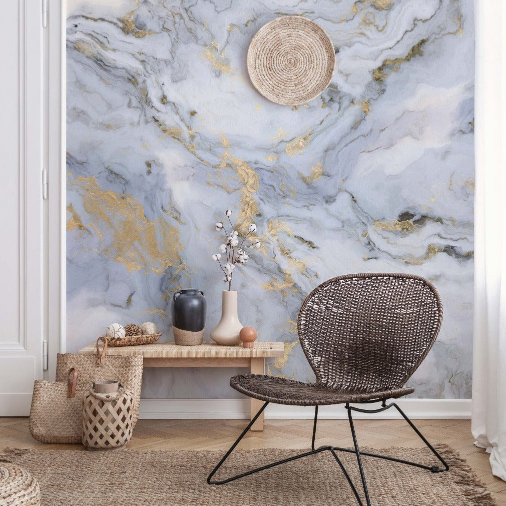 A modern room featuring the Decor2Go Wallpaper Mural in shades of gray and blue with gold veins, a dark rattan chair, decorative vases on a wooden bench, and woven baskets complete the serene.