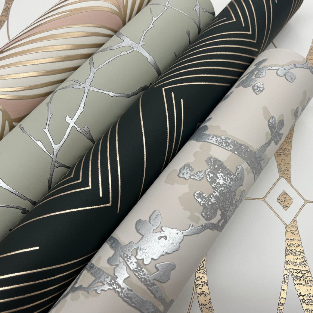 Close-up of four rolls of York Wallcoverings' modern metallic wallpaper. Designs incorporate geometric lines, branches, and abstract shapes in gold and silver on green, beige, and cream. Included is the Eucalyptus & Silver Trees Silhouette Wallpaper for added elegance.