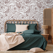 Bedroom - A cozy bedroom featuring a double bed with green bedding and a beige blanket, a wooden headboard, and unique Exotic Plants Sketch Wallpaper Mural by Decor2Go. A wicker room divider and a matching chair add a