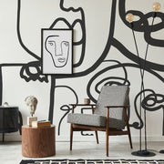 Living Room - A modern living room with a Decor2Go Wallpaper Mural on the wall, a framed minimalist face artwork, a houndstooth armchair, a side table with books, and a minimalist design sculpture.