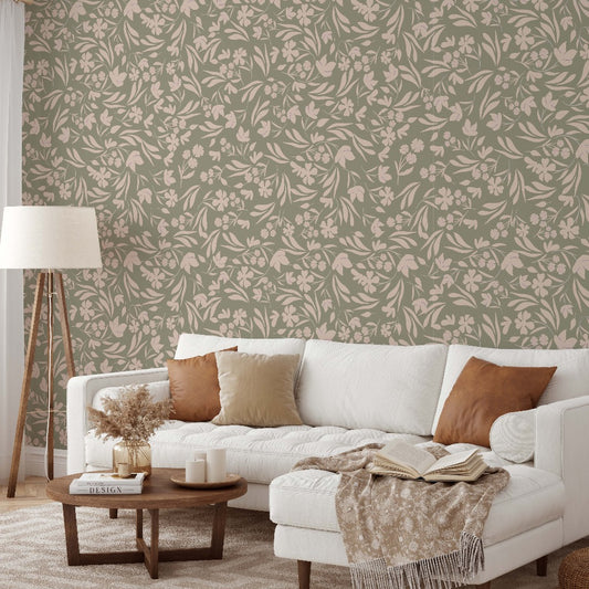 A cozy living room featuring a white sofa with brown and beige cushions, a wooden coffee table with books and decor, a floor lamp, and a wall with Floral Bliss Wallpaper Mural by Decor2Go Wallpaper Mural on a green background.