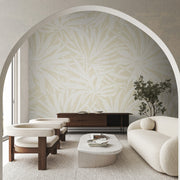 Living Room - A modern with cream armchairs, a curved sofa, wooden sideboard, minimalist coffee table, and York Wallcoverings' Floral Canopy Beige Wallpaper Mural on a feature wall, viewed through an arched doorway