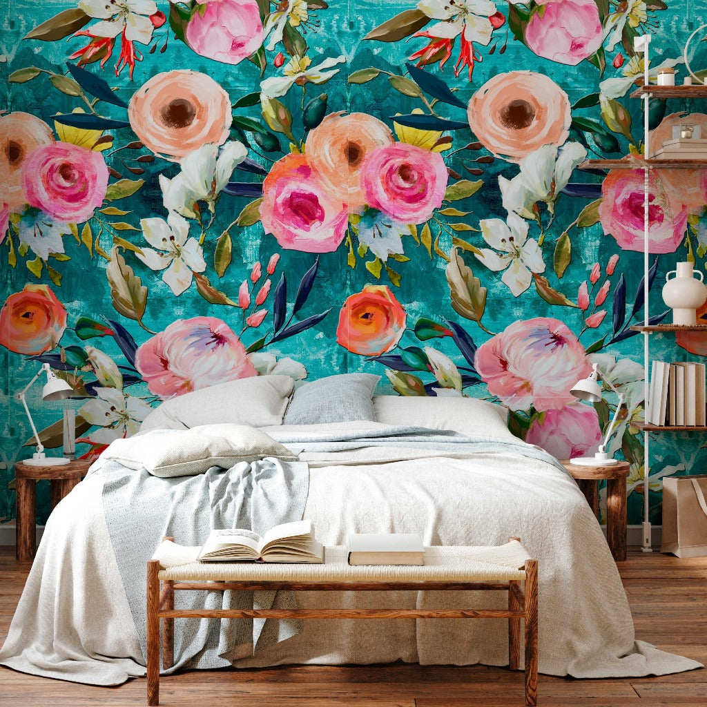 A cozy bedroom featuring a large bed with gray and white bedding, set against a vibrant Decor2Go Wallpaper Mural with large pink and peach blooms. A wooden bench with an open book sits at the foot of the bed.