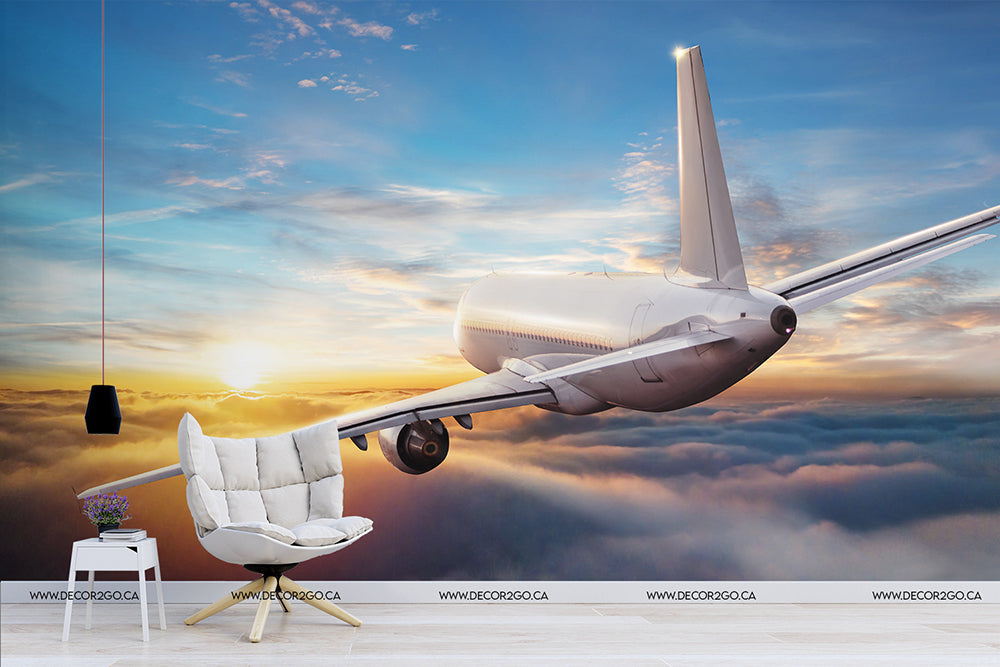Surreal image of an airplane's tail and wing extending from a cloudy sky into a cozy living room with a stylish white chair, a small table, and a hanging lamp, blending outdoor flight with Decor2Go Wallpaper Mural.