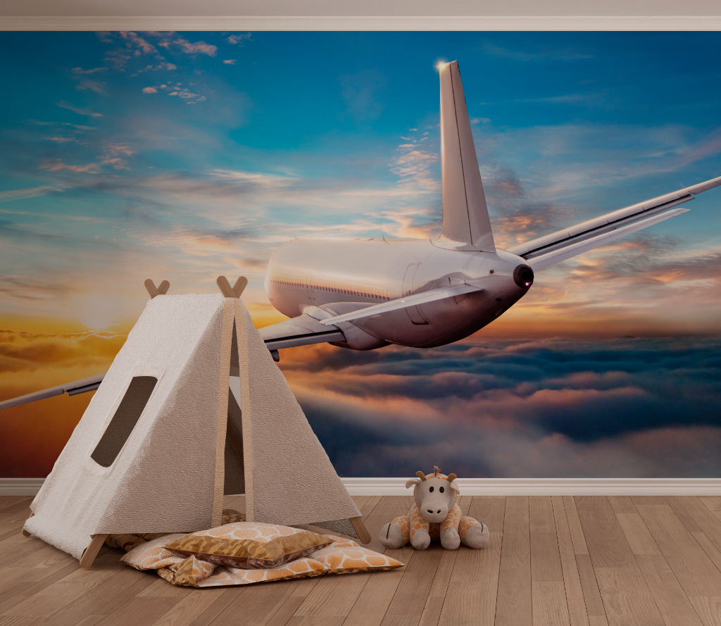 A surreal image of a large airplane flying low in a room with a wooden floor, against Decor2Go Wallpaper Mural's Flying Above the Clouds Wallpaper Mural. A small teepee and a plush giraffe toy sit on the floor.