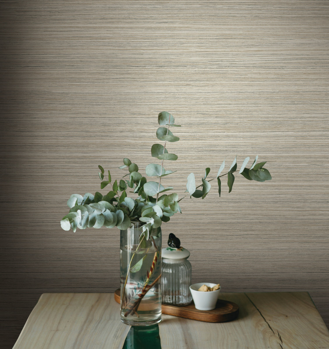 brown grasscloth wallpaper on the wall. green leaves on front table