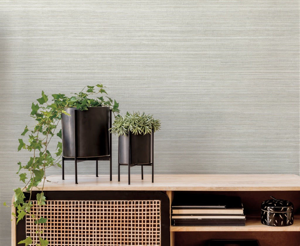 Beige grass sand wallpaper on the wall, table in the front with green leaves in a pot