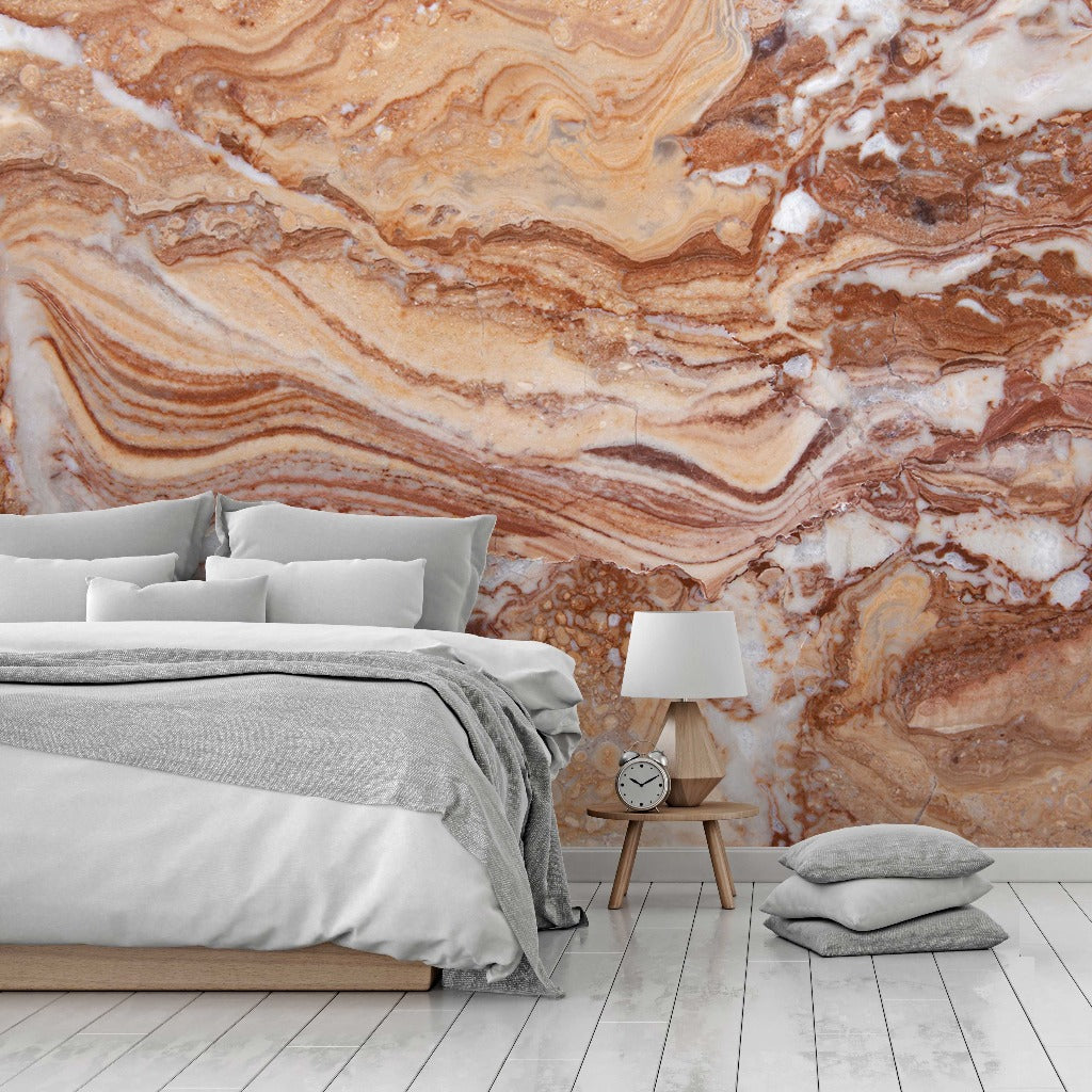 A modern bedroom featuring a bed with gray bedding and a Gemstone Diffused Marble Wallpaper Mural in earthy tones from Decor2Go Wallpaper Mural. A wooden bedside table with a lamp and clock is next to the bed, and a