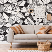 Living Room - A modern living room featuring a gray sofa with patterned cushions, a wicker basket, and a striking Decor2Go Geometric Black & White Wallpaper Mural.