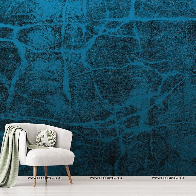 Living Room - A minimalist living room featuring a white armchair with a green blanket and a cushion, beside a small table with a plant, against a Decor2Go Glacial Frost Wallpaper Mural feature wall with crack patterns.