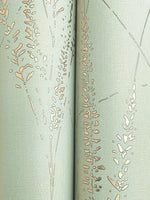 Close-up of Graceful Willow Lagoon Wallpaper by York Wallcoverings, featuring a light green hue with subtle texture and abstract beige and tan grass-like designs. The seam between two panels is visible down the center. Covers 60 SqFt.