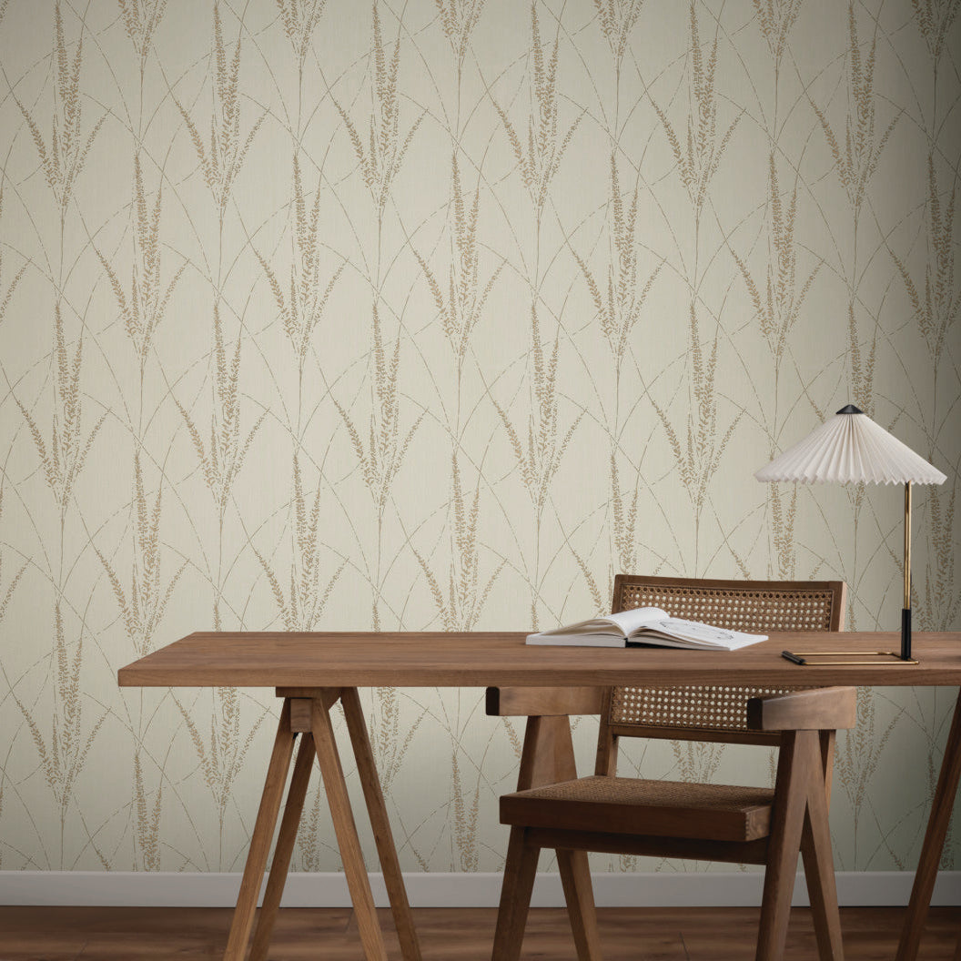 A wooden desk with a book, glasses, and a white lamp sits beside a wooden chair. The background features York Wallcoverings' Graceful Willow Stone Wallpaper (60 SqFt) in light beige with a subtle botanical leaf pattern.