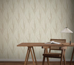 A wooden desk with a book, glasses, and a white lamp sits beside a wooden chair. The background features York Wallcoverings' Graceful Willow Stone Wallpaper (60 SqFt) in light beige with a subtle botanical leaf pattern.