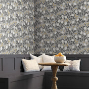 A cozy corner with dark wainscoting, white textured cushions on a built-in bench, a round wooden table with a bowl of oranges, and York Wallcoverings' Gray Peonies Wallpaper (60 SqFt) creating an inviting atmosphere.
