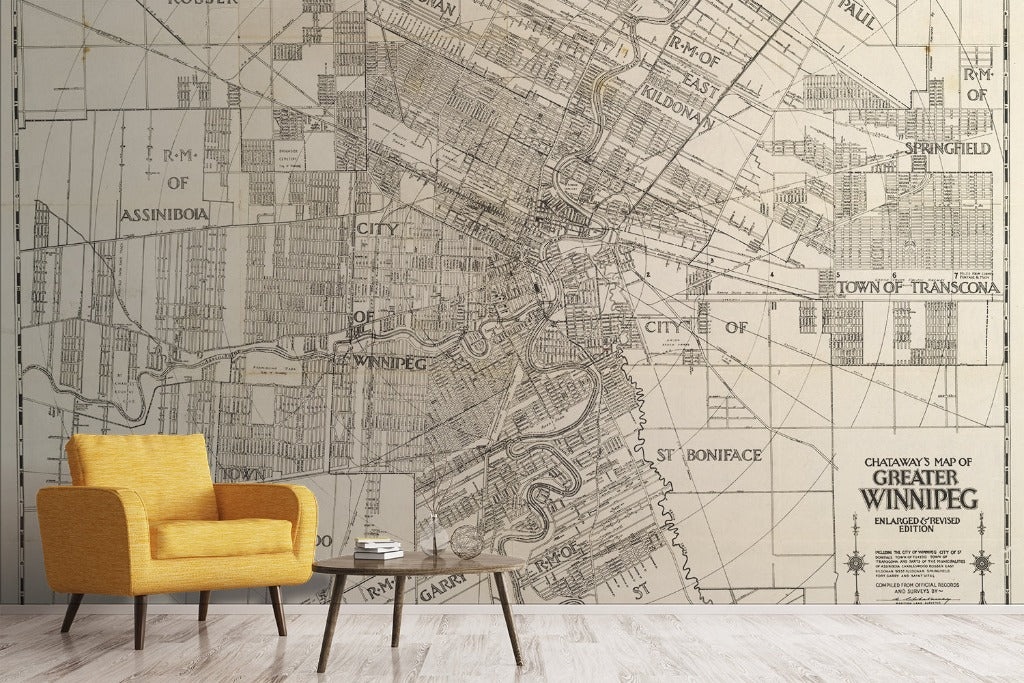 Living Room - A stylish living room features a Decor2Go Wallpaper Mural showcasing the Greater Winnipeg Wallpaper Mural, enveloping an entire wall. In the foreground, there's a modern, mustard-yellow armchair and a small wooden coffee table on a light wooden floor.
