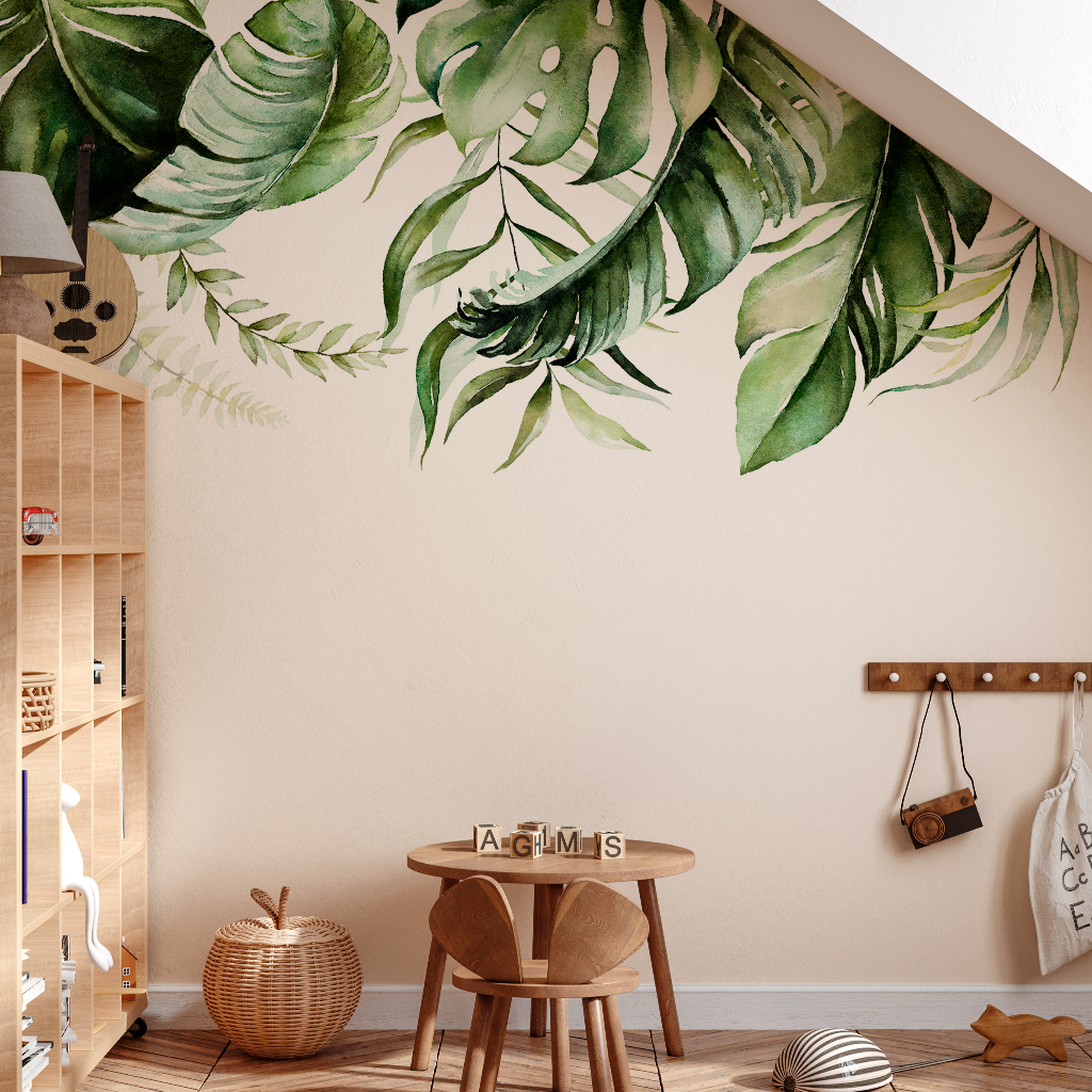 A cozy children's playroom with a "Green is in the air" wallpaper mural from Decor2Go on the wall, a wooden table with alphabet blocks, a toy basket, and shelves with books and toys.
