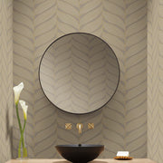 Bathroom - A modern features a round mirror, York Wallcoverings' Grey & Gold Luminous Leaves wallpaper, and a black vessel sink. Two gold faucets from the Modern Metals Collection adorn the wall. A minimalistic soap dish and vase of white flowers enhance the wooden countertop's elegance with metallic accents
