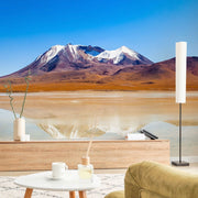 Living Room - A tranquil living room overlooking a stunning landscape with snow-capped mountains and a reflective lake, featuring a modern wooden console, cozy seating, and the Decor2Go Wallpaper Mural.