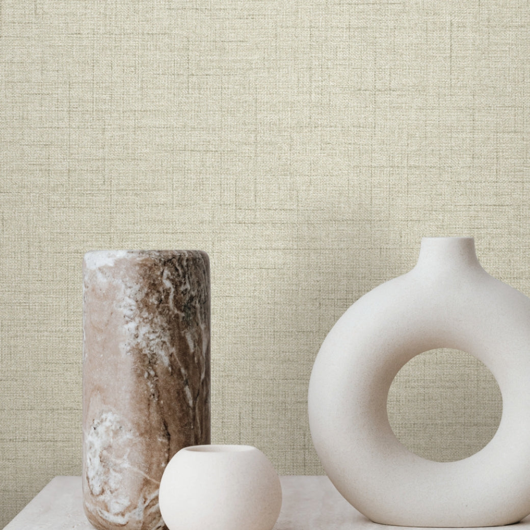Three minimalist vases—one tall and marbled, one small and round, and one large with a circular opening—sit on a light surface against York Wallcoverings’ Hillswick Tweed Beige Wallpaper (60 SqFt).