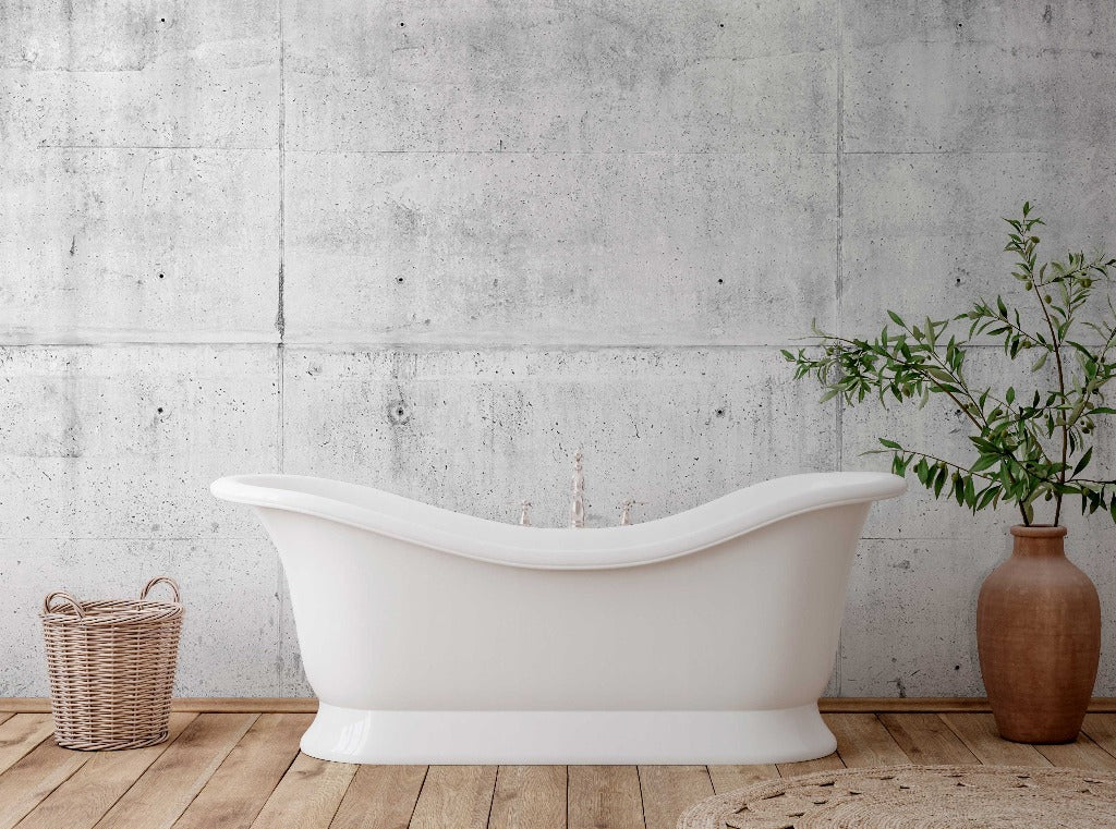 A modern white bathtub stands against a Decor2Go Wallpaper Mural, accompanied by a wicker basket and a large clay pot with a green plant, on a woven mat.