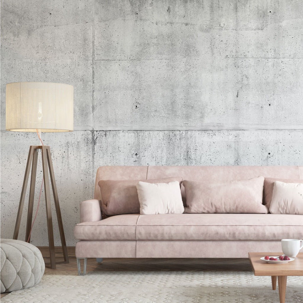 Modern living room with a blush pink velvet sofa, white cushions, a tripod floor lamp, and a Decor2Go Wallpaper Mural. A cup of tea and a plate lie on the sofa.