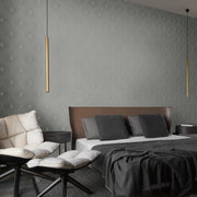 Bedroom - A modern features a large bed with a brown leather headboard and dark pillows. Two sleek pendant lights illuminate a cushioned chair against metallic York Wallcoverings' Light Grey & Silver Harlowe Wallpaper, enhancing the beige wall's subtle diamond pattern