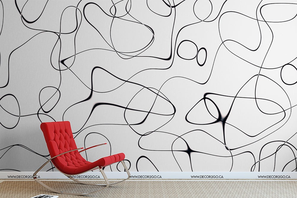 A modern red lounge chair sits against a wall with the "Lovely Swirls Wallpaper Mural" by Decor2Go Wallpaper Mural, featuring large-scale, black and white abstract line patterns that exemplify fluidity of movement.