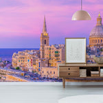 Modern living room with stylish furniture overlooking a scenic city with historic architectural buildings under a vibrant sunset sky, enhanced by a Decor2Go Wallpaper Mural.