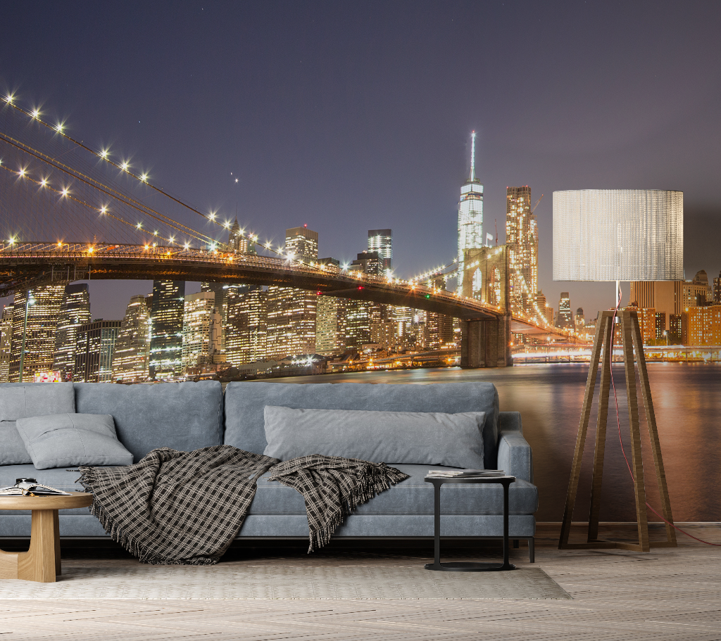 Living Room - A contemporary living room with a large gray sofa and floor lamp, superimposed against a panoramic city view mural of the Brooklyn Bridge and Manhattan skyline featuring the Decor2Go Wallpaper Mural's Manhattan's Night Sky Wallpaper Mural.