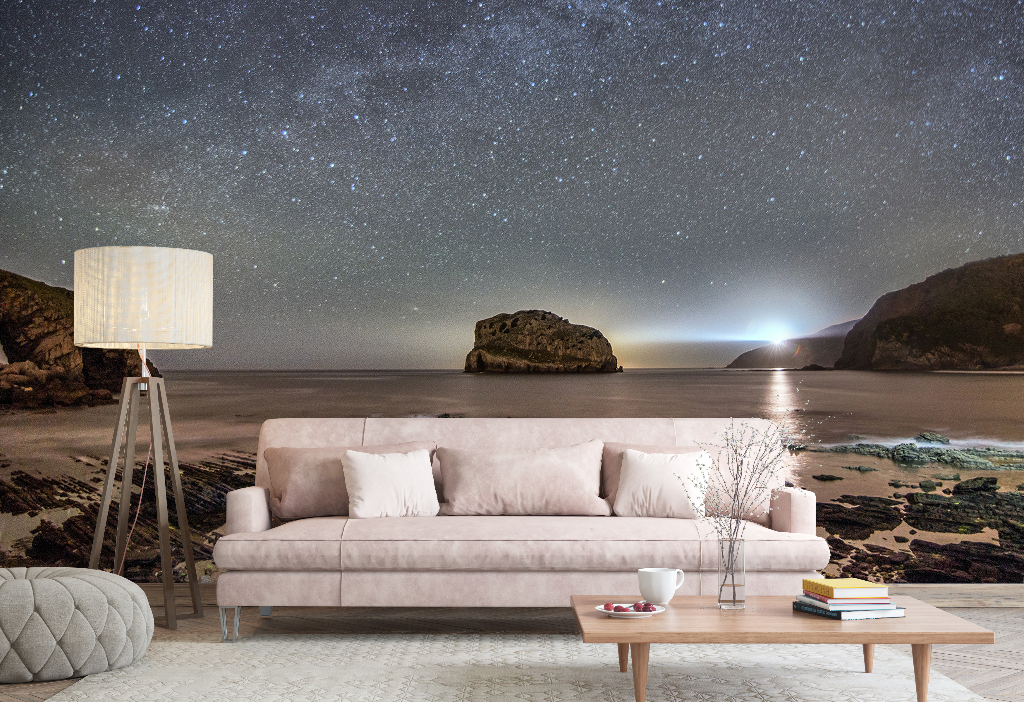Living Room - A serene living room setup with a pastel-pink couch, lamp, and astrology-themed decor items, juxtaposed against a surreal backdrop of a Milky Way Galactic Coast wallpaper mural depicting a starry sky and a moon by Decor2Go Wallpaper Mural.