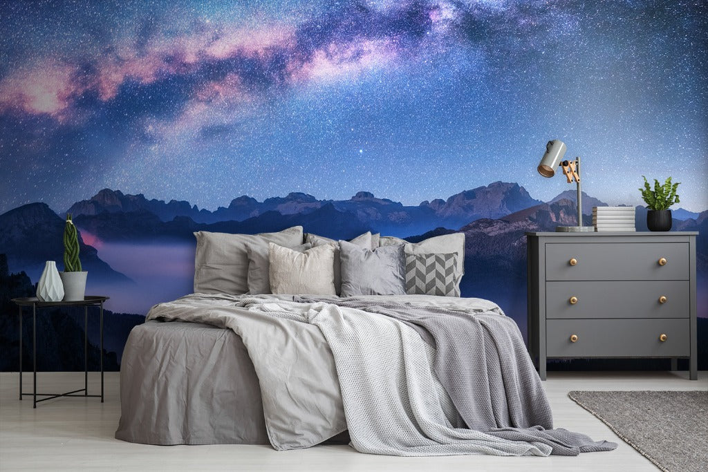 Bedroom - A cozy bedroom featuring a bed with gray linens under a vibrant Decor2Go Wallpaper Mural with mountain landscape. A side table, lamp, gray dresser, and decorative plants complement the serene setting.