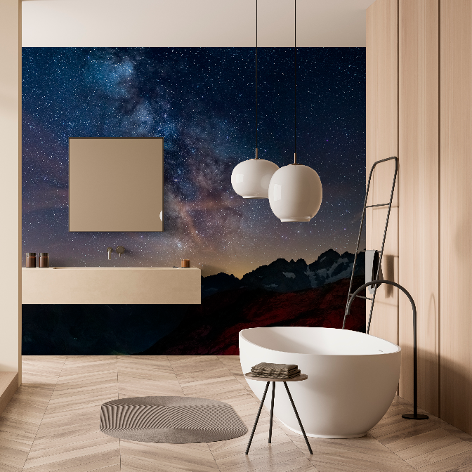 Modern bathroom with a freestanding tub, wooden floor, and a shower space. Features a striking Decor2Go Wallpaper Mural with stars and mountains, and elegant hanging lamps.