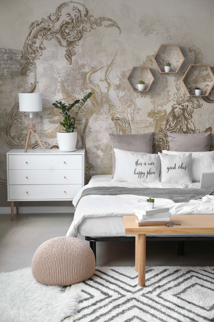 A modern bedroom featuring a white bed with decorative pillows, a wooden bedside table with a lamp, a dresser, and Decor2Go Wallpaper Mural, accompanied by geometric shelves with plants.