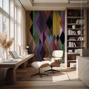 This contemporary space highlights the Modern Geometric Shapes Wallpaper Mural by Decor2Go, featuring a large window and a vibrant color palette. It includes a wooden desk with a computer and lamp, complemented by a cozy white lounge chair with an ottoman atop a rug. Shelves adorned with books and decor items add charm, while pampas grass in a vase brings a natural element to the room.