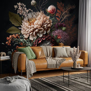 Living Room - A cozy living room is highlighted by a brown leather sofa adorned with green and gray pillows and blankets. Behind it, the wall exudes a sophisticated ambiance featuring the Moody Floral Elegance Wallpaper Mural by Decor2Go. A round coffee table is topped with a vase of dried plants, while sunlight streams through the window.