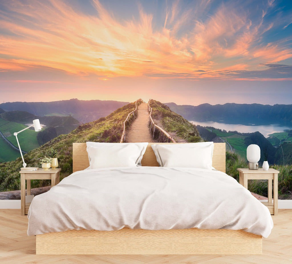 Bedroom - A serene bedroom with a large bed facing a wall-sized Decor2Go Wallpaper Mural of a Mountaintop Trail overlooking a mountain pathway leading into a sunset with distant water views.