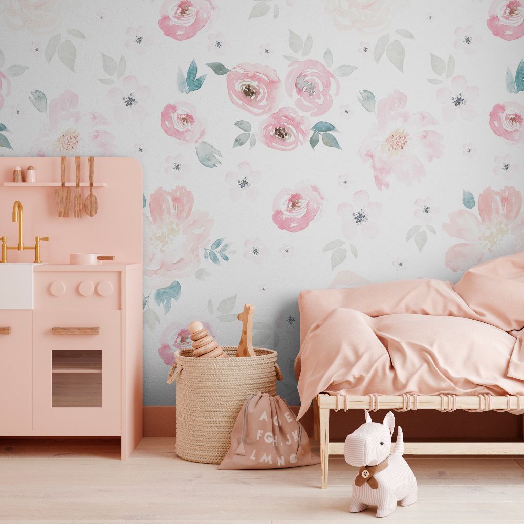 A cozy children's room featuring a pastel pink color scheme with a Decor2Go Wallpaper Mural, matching bed linen, a small wooden bed, a toy kitchen set, and a stuffed animal on the