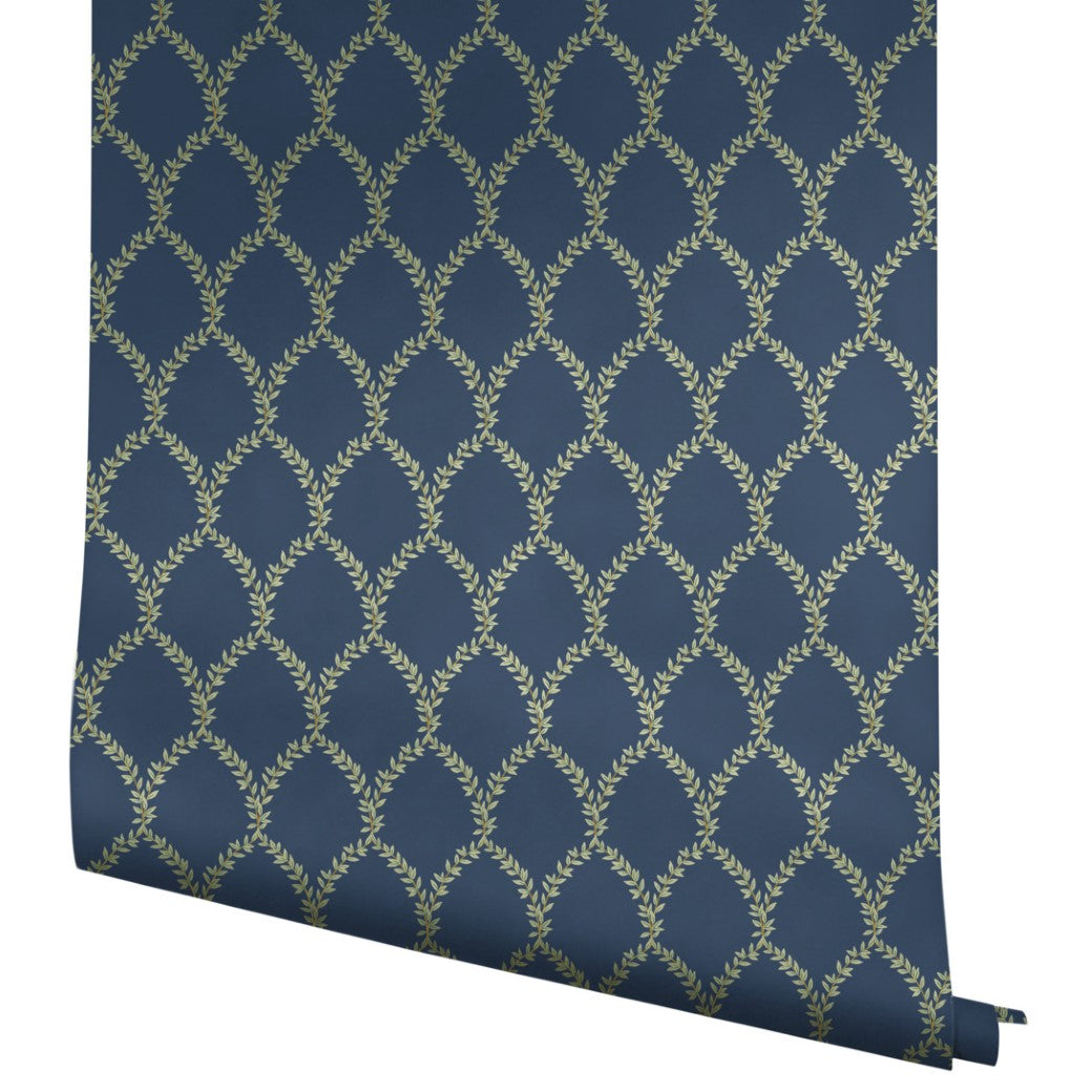 A partially unrolled Navy Laurel Wallpaper (60 SqFt) by York Wallcoverings shows its repeating gold laurel wreath design on a dark blue background.