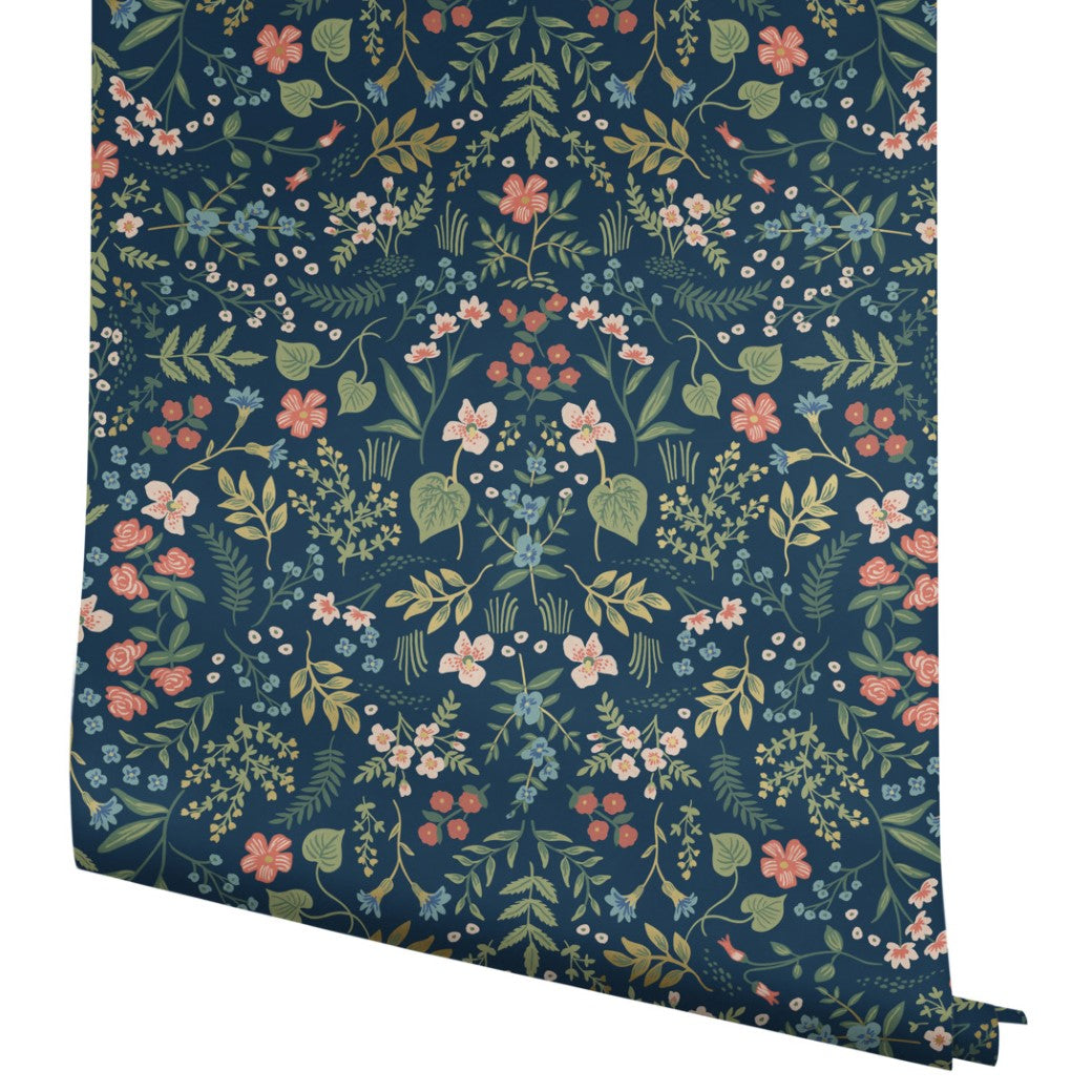 York Wallcoverings Navy Wildwood Wallpaper (60 SqFt) features a symmetrical floral pattern with pink, yellow, and white flowers and green leaves on a dark blue background—perfect for adding botanical charm to any space.