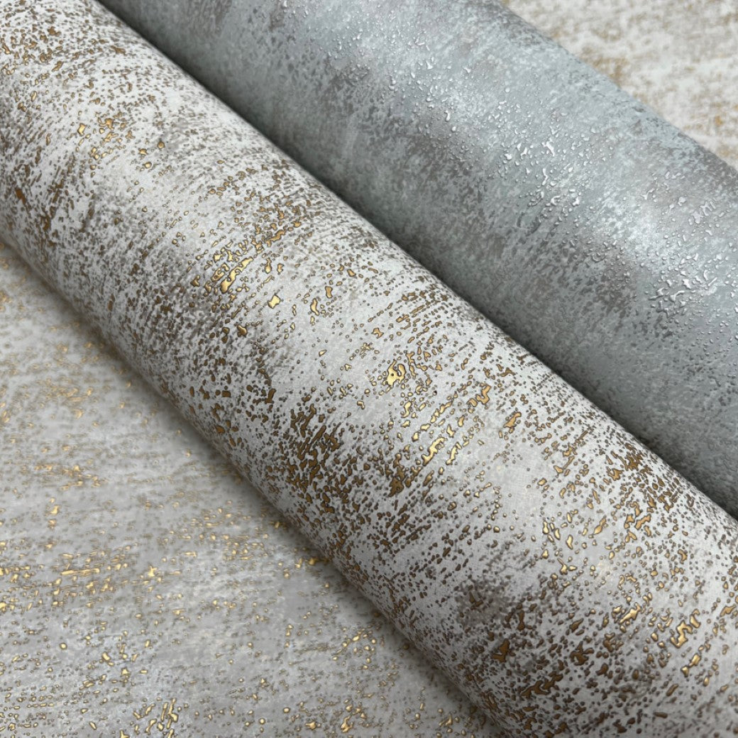 Two rolls of York Wallcoverings' Neutral & Gold Shimmering Patina Wallpaper (57 SqFt) rest on a matching background. The silver and gold wallpapers feature a speckled metallic finish, adding an elegant shimmer ideal for contemporary spaces.