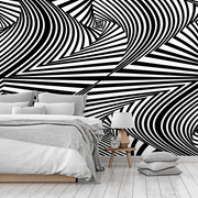 Bedroom - A modern bedroom with a striking black and white Decor2Go Optical Illusion Wallpaper Mural design, featuring a minimalist bed with gray bedding, and a small wooden bedside table with a lamp and clock.