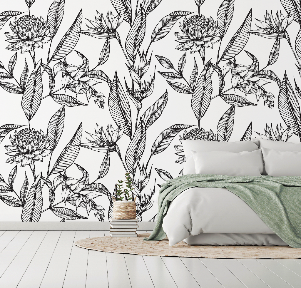 A modern bedroom with a white wall decorated with an artistic Decor2Go Paradise Flower Wallpaper Mural design, featuring a double bed with white bedding and a green throw, and a small wooden stool with books and a plant.