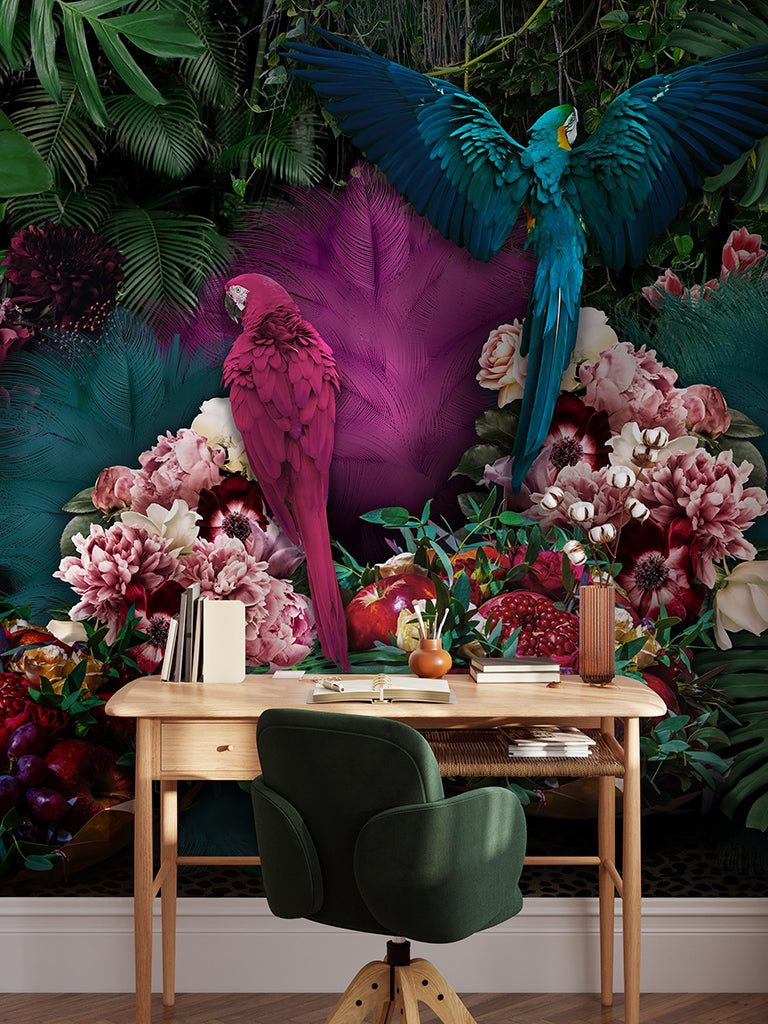 A vibrant image showcasing a workspace with a wooden desk and a green chair, against a backdrop of lush tropical vegetation and oversized flowers. Two majestic parrots, one pink and one blue, add a dynamic touch to the Decor2Go Parrot Paradise Wallpaper Mural.