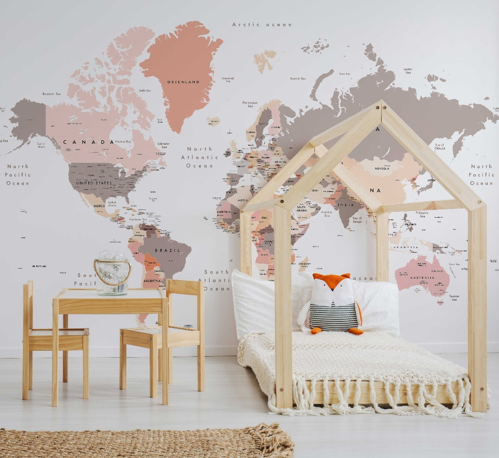 A child's bedroom with a wooden house-frame bed, Peach World Map Wallpaper Mural from Decor2Go Wallpaper Mural, a small table and chair set. The decor includes a stylish rug and soft pillows.