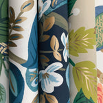 Four rolls of York's Periwinkle Peacock Wallpaper showcase floral Chinoiserie-inspired designs with leaves and flowers in blue, green, gold, and white on varied backgrounds. Each roll covers 60 SqFt with unique botanical patterns.