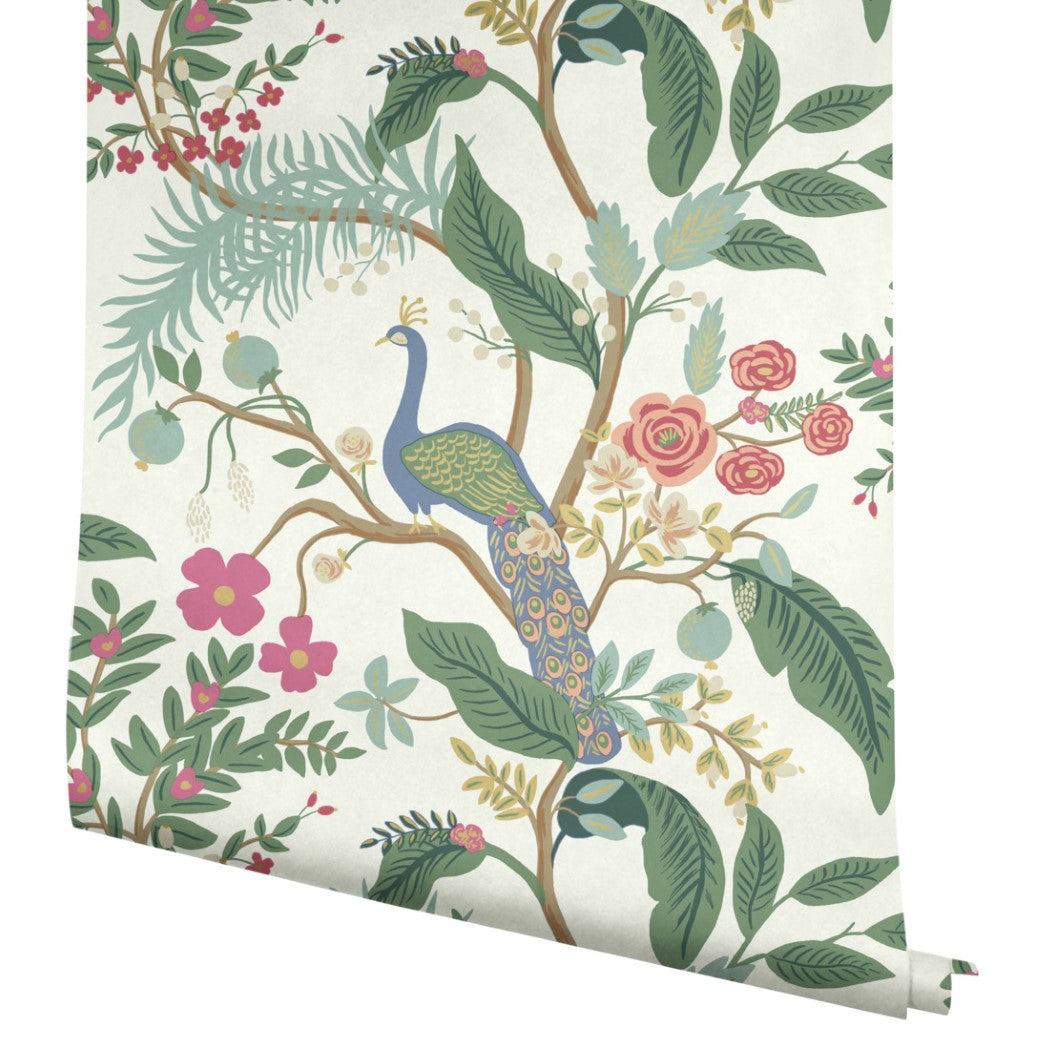 The Periwinkle Peacock Wallpaper (60 SqFt) by York showcases a Chinoiserie design with a peacock on a tree branch among colorful flowers and lush green leaves on a white background.