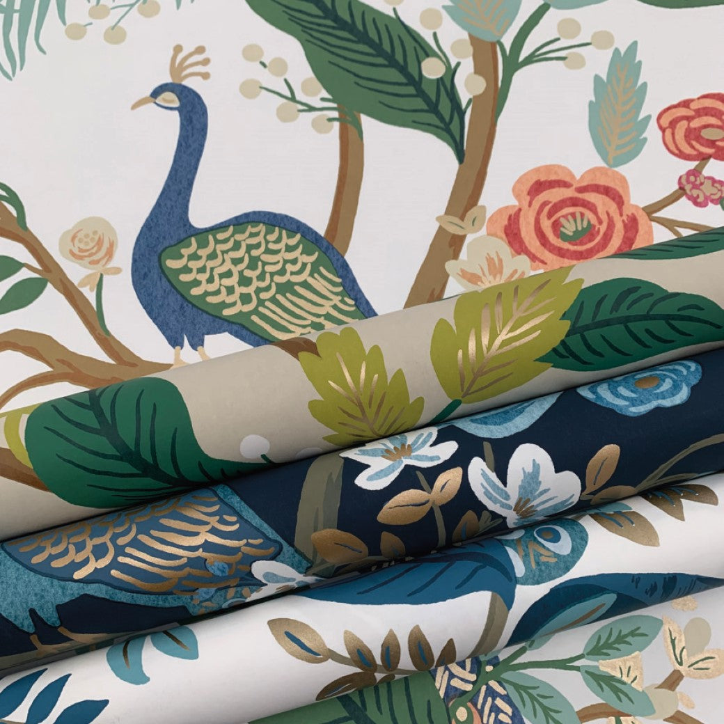 Rolled Periwinkle Peacock Wallpaper (60 SqFt) by York Wallcoverings features colorful peacocks, flowers, and leaves in blue, green, cream, and coral tones, displayed in layers to highlight its elegant chinoiserie patterns.
