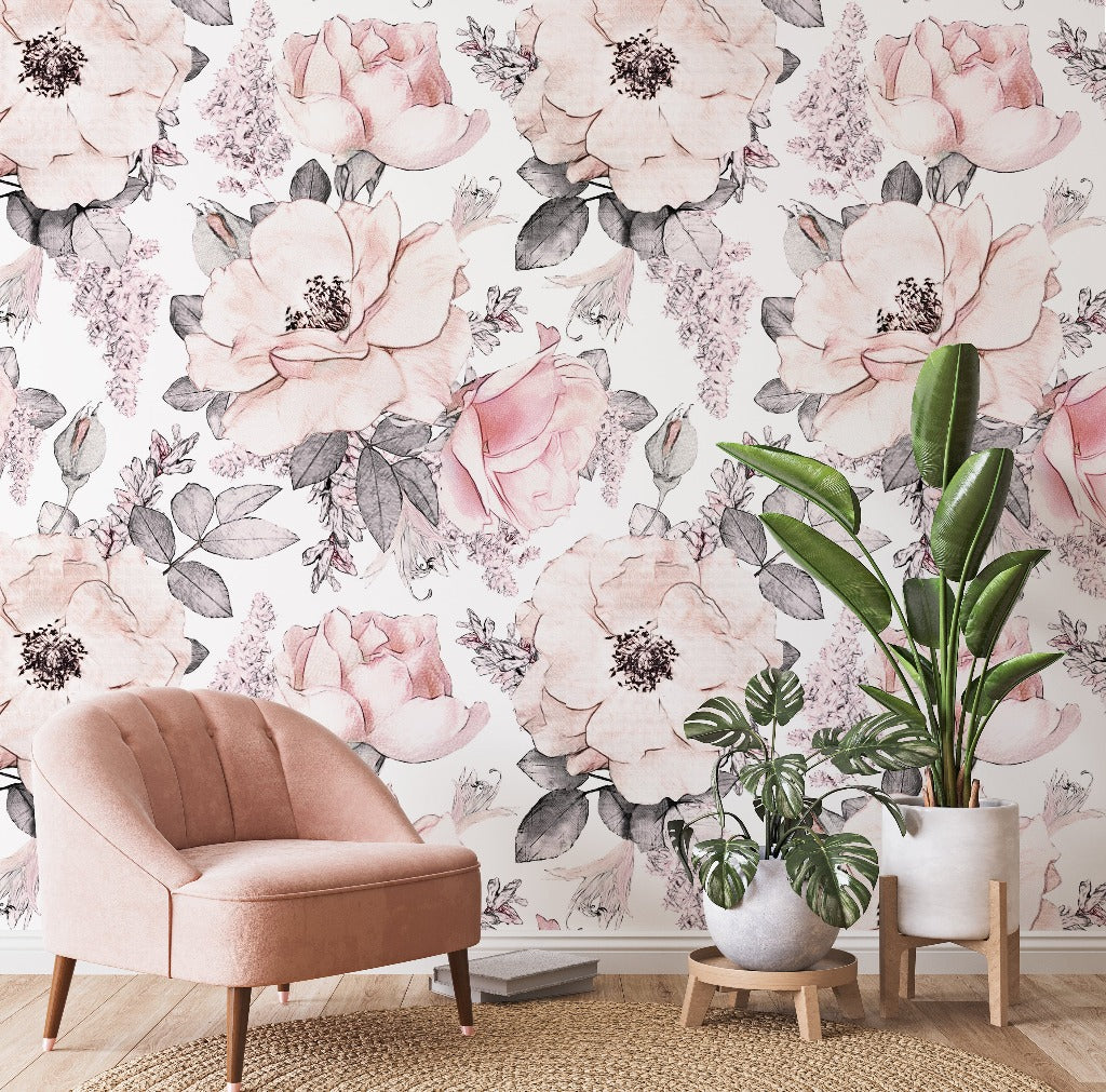 A cozy room corner featuring a blush pink armchair and two potted plants against a Decor2Go Wallpaper Mural with large pink and white roses and delicate grey leaves.